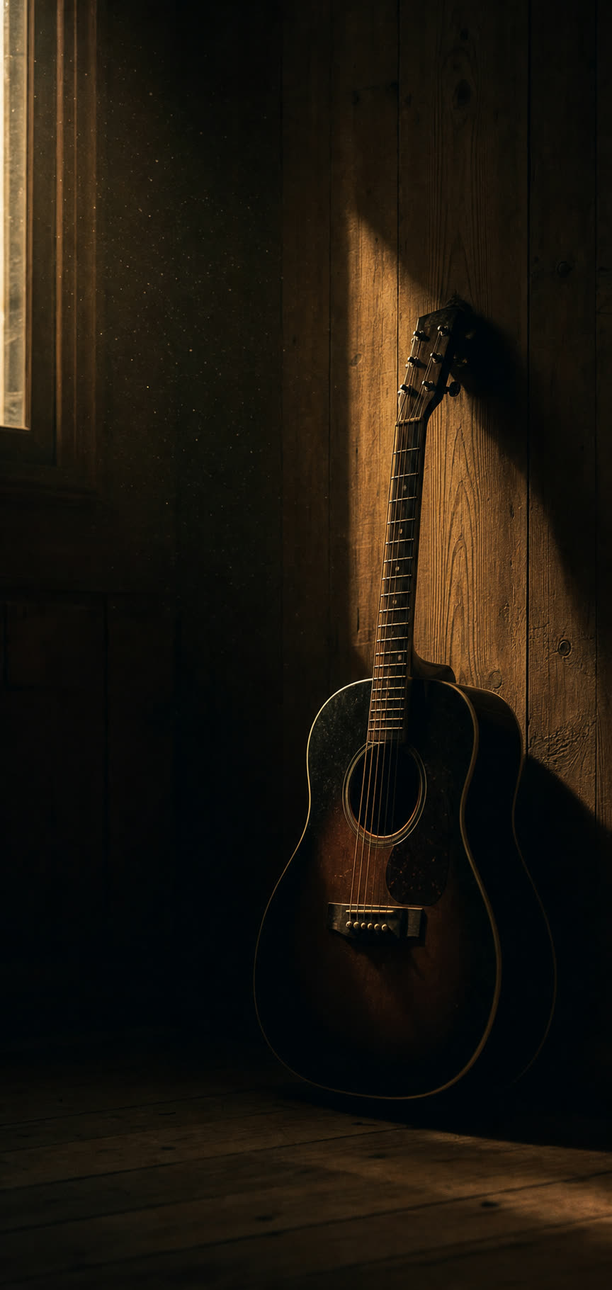 An acoustic guitar in a dim wood-panelled room lit by a narrow shaft of daylight.
